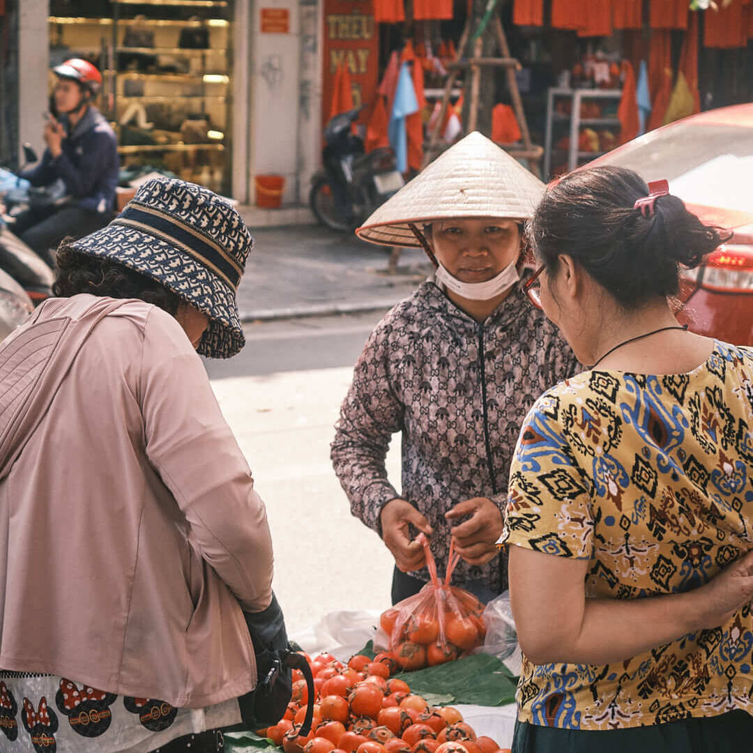 A street vendor selling persimmons, capturing the intimate and colorful moments of Hanoi’s vibrant markets.