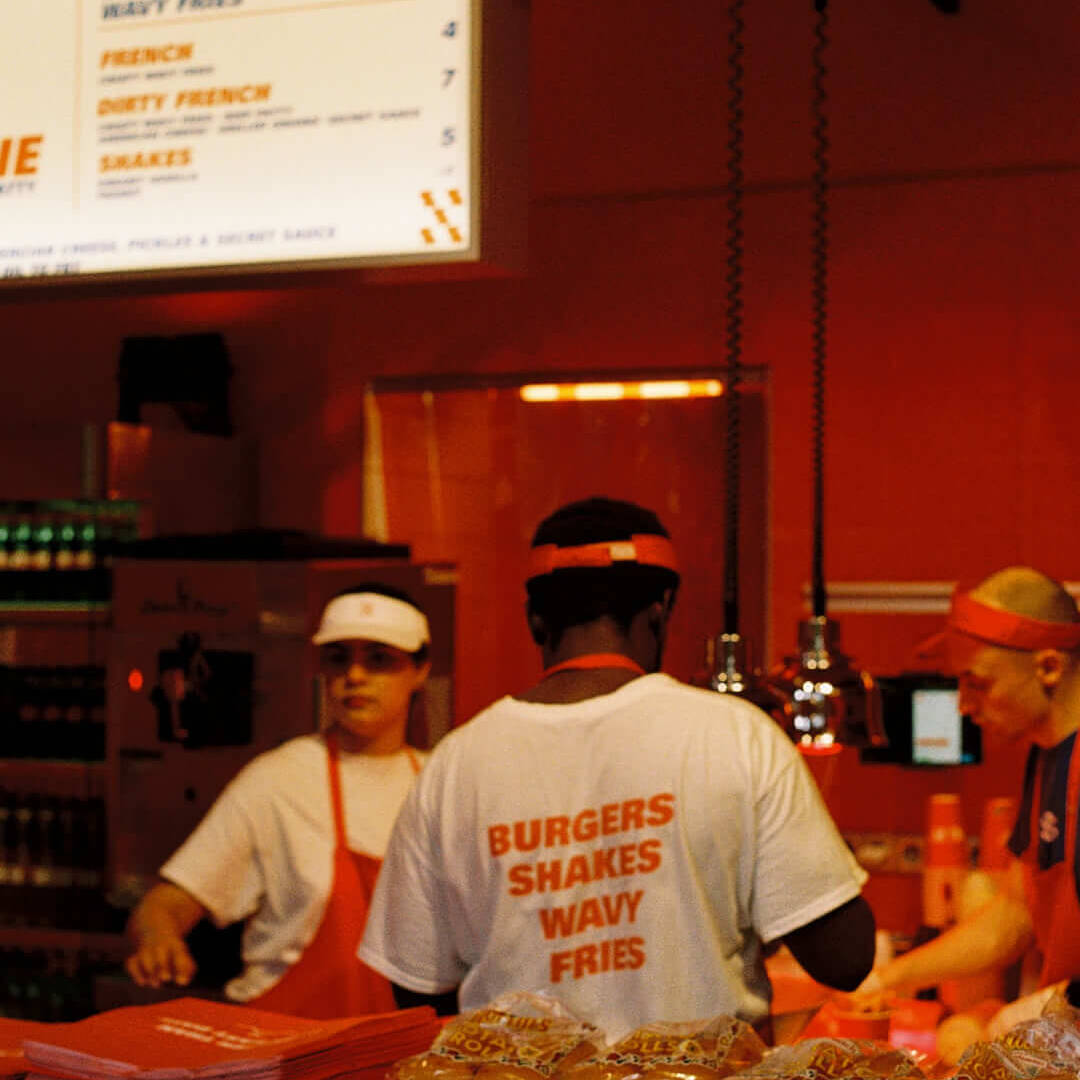 Inside the restaurant, staff wearing white shirts with red text reading 