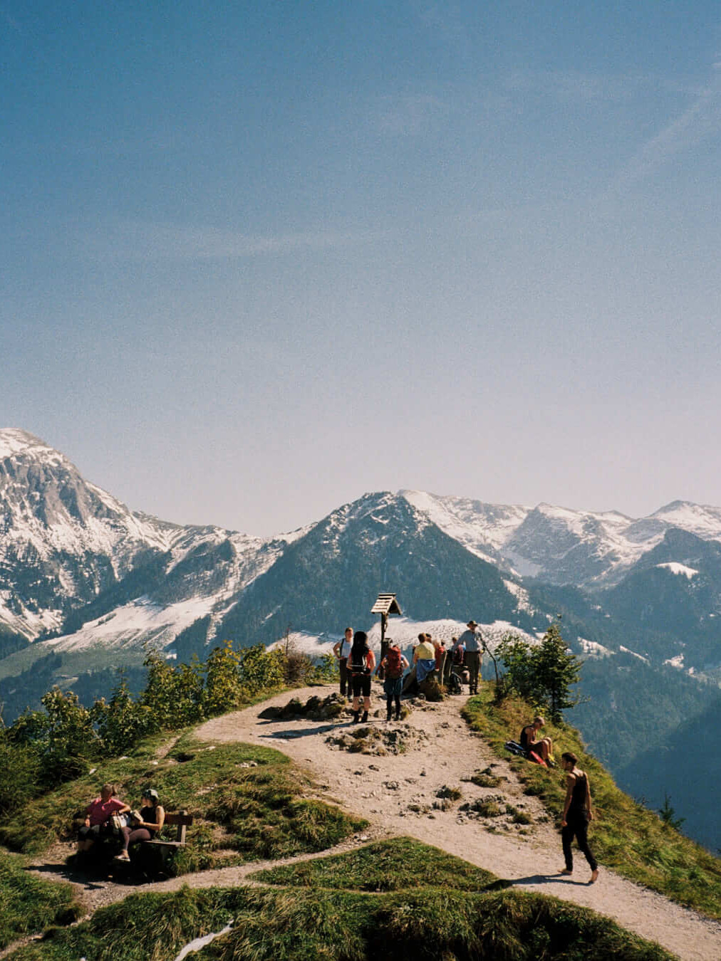 A group of hikers enjoying the alpine summit, the joy and serenity of the outdoors encapsulated in a timeless film aesthetic.