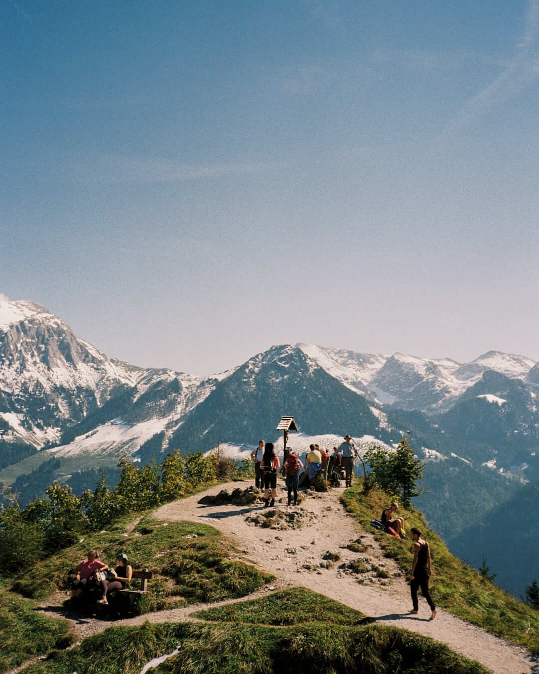 A group of hikers enjoying the alpine summit, the joy and serenity of the outdoors encapsulated in a timeless film aesthetic.