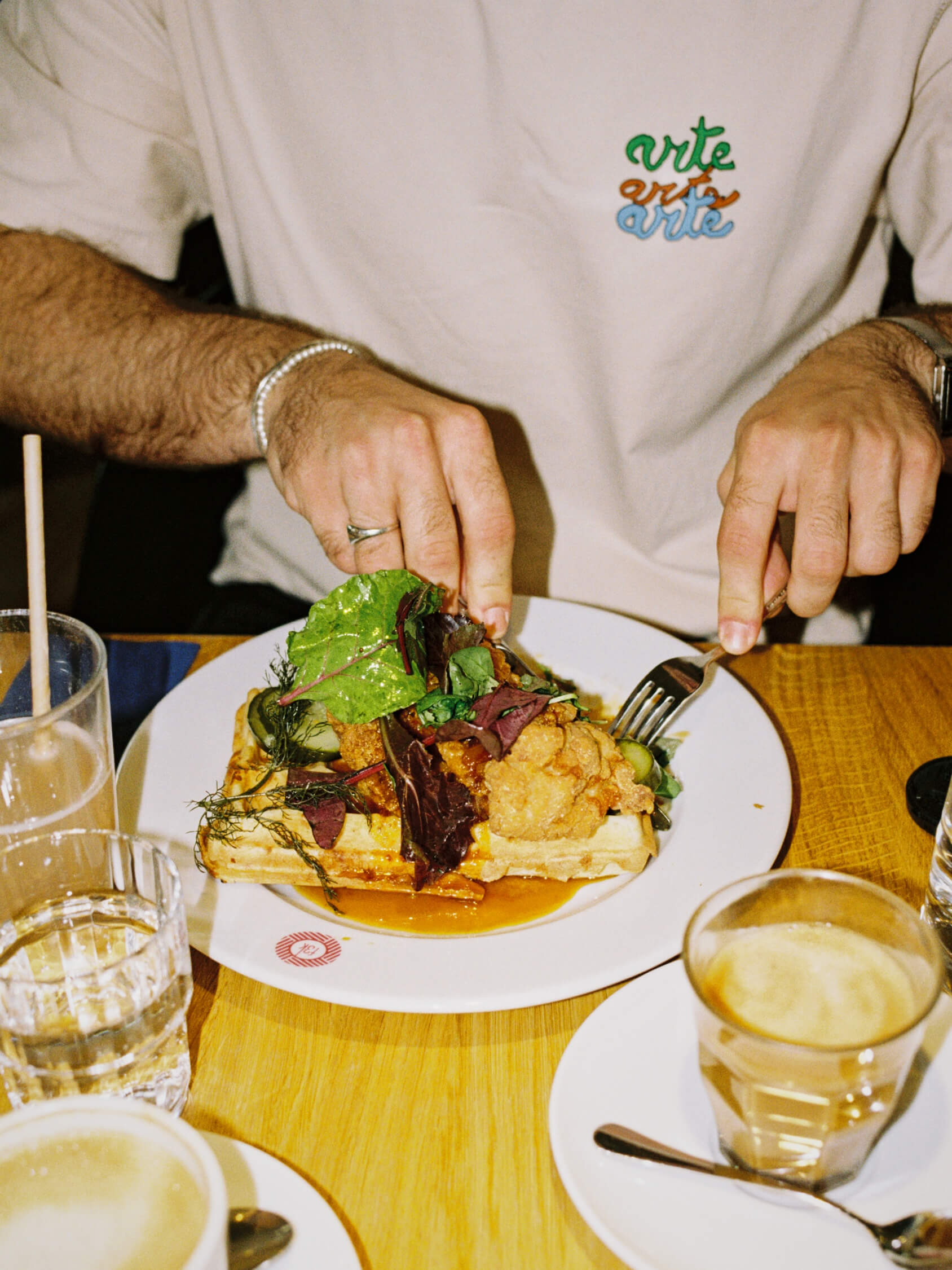 Crispy fried chicken waffle dish served with fresh herbs at Frühstück 3000 Kreuzberg, shot on Kodak Gold 200 film.