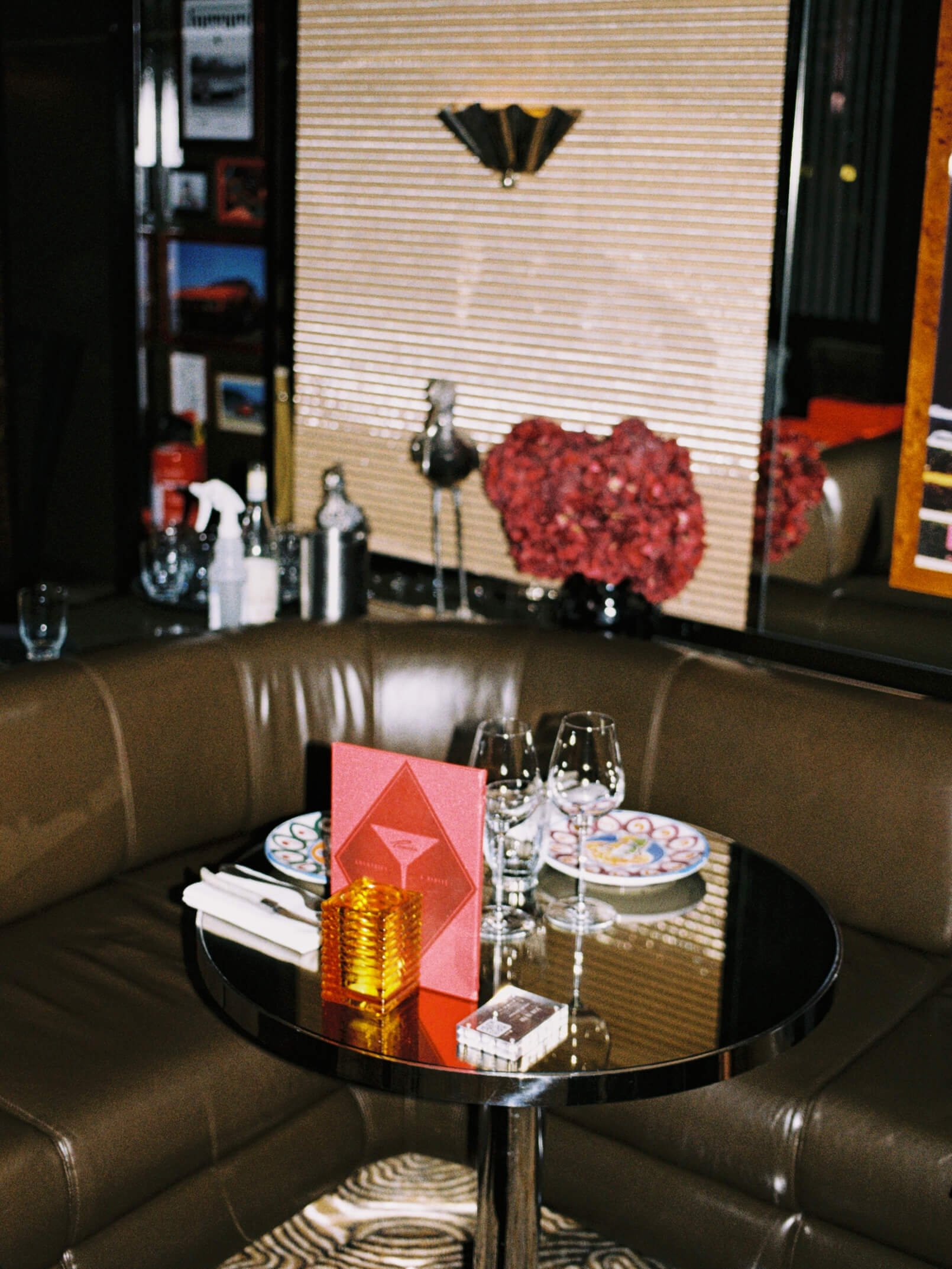 Aesthetic dinner table setting with white tablecloth, hand-painted ceramic plates, and velvet chair at Pamela Berlin.