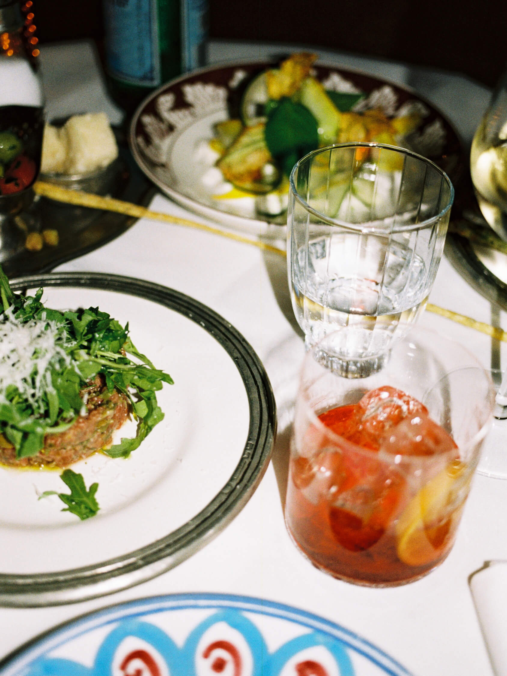 Close-up of beef tartar topped with greens alongside an iced Negroni cocktail at Pamela restaurant.