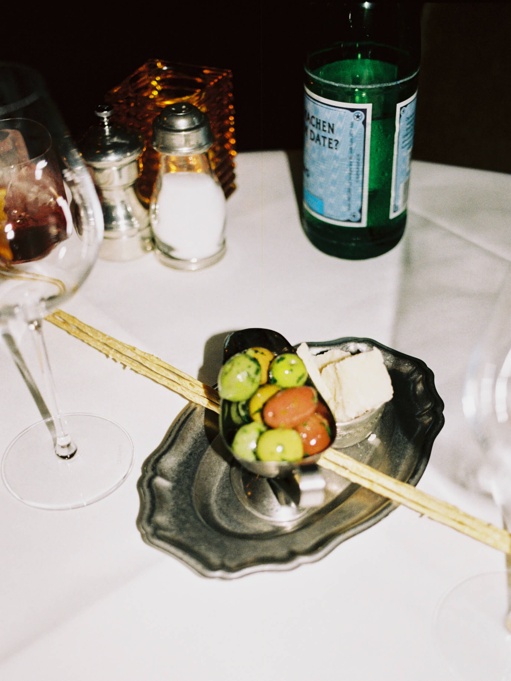 Silver appetizer dish with green olives, butter, and breadsticks served at Pamela Italian restaurant in Berlin on film.